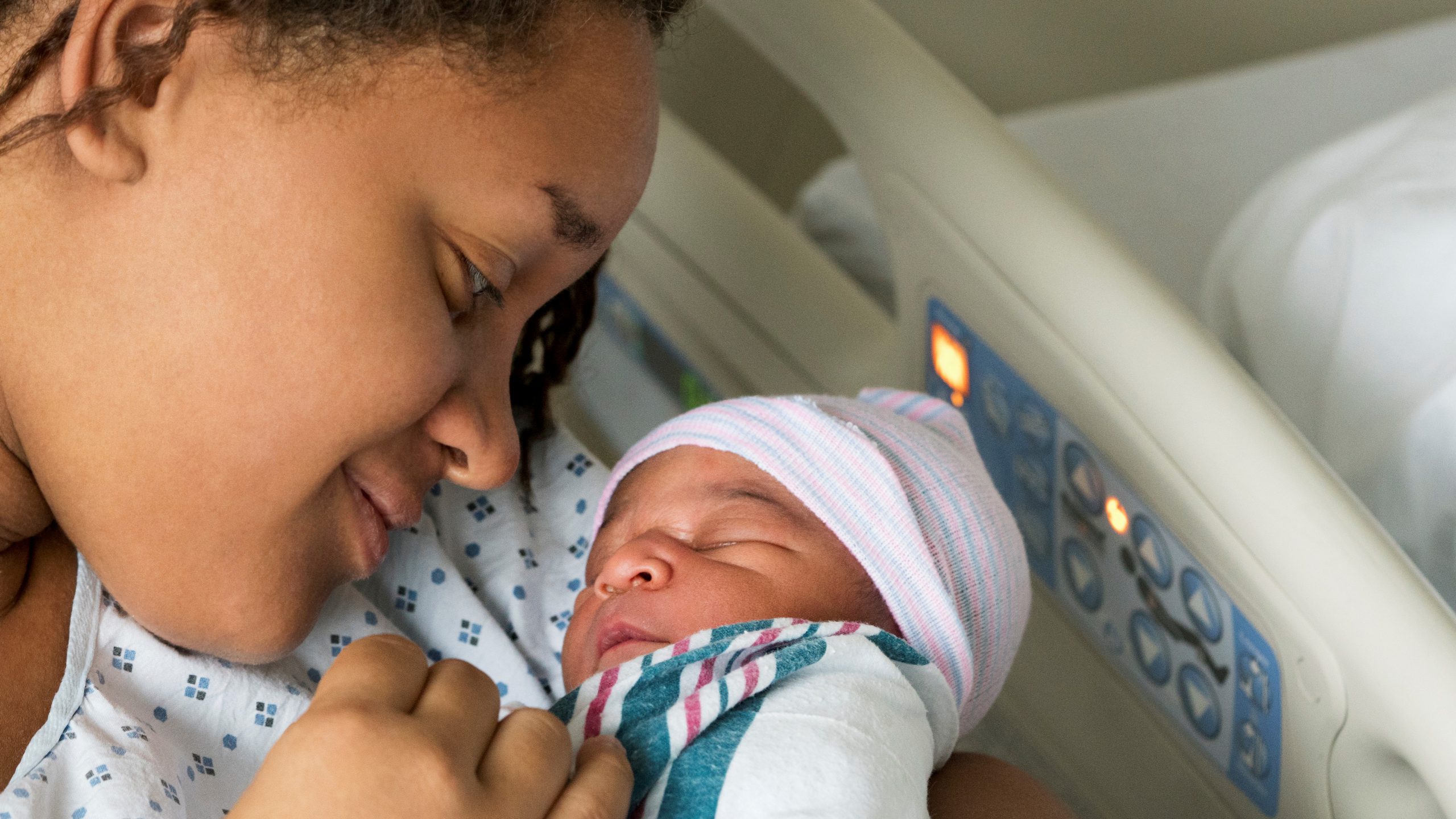 An image of a mother cradling newborn son in hospital.