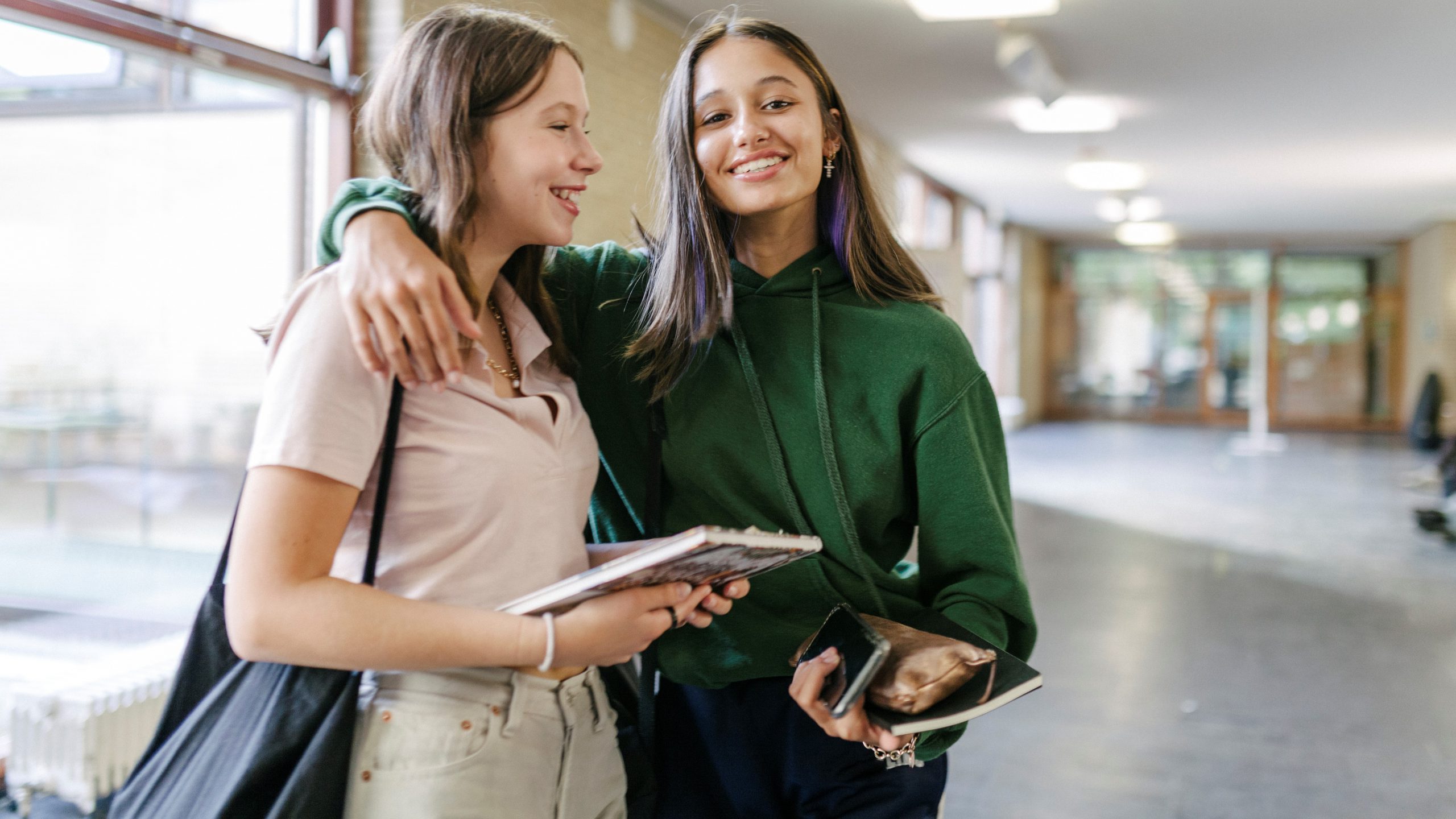 Two High School students hugging each other while on their way to their next class.