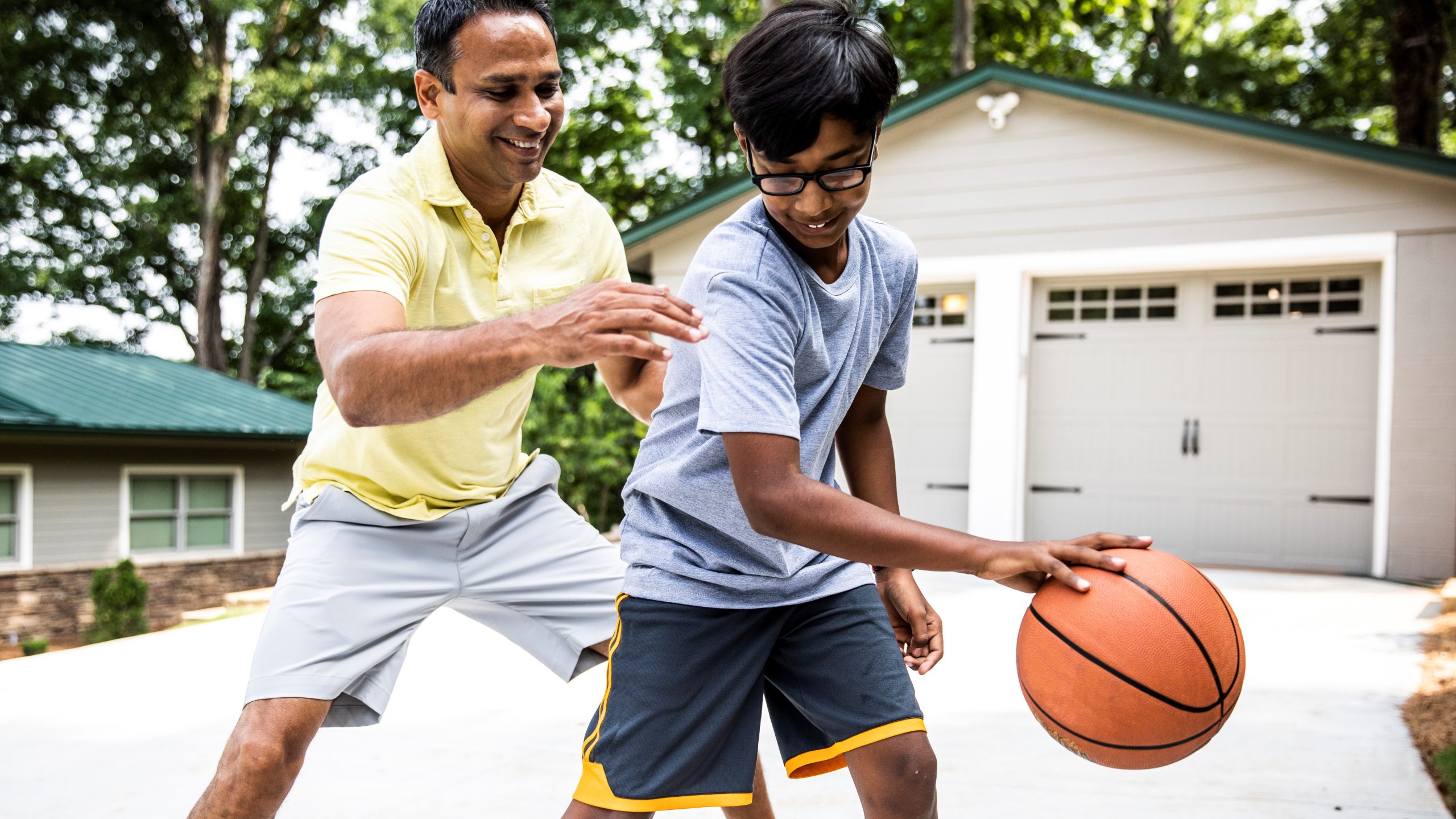 Father and son playing basketball in driveway