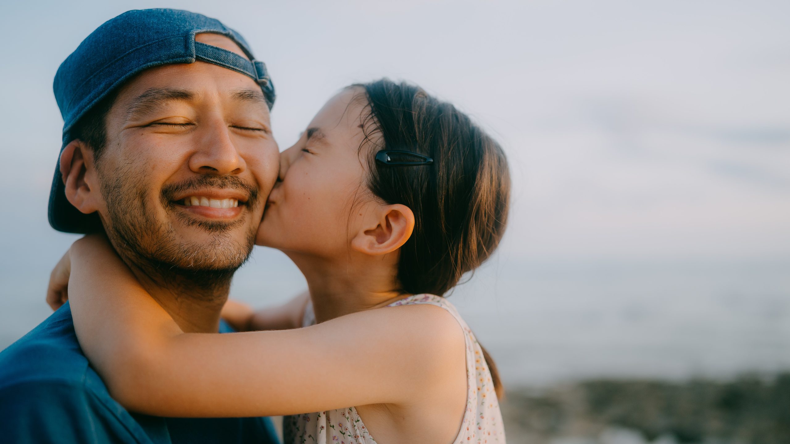 Cute young daughter kissing her father on beach