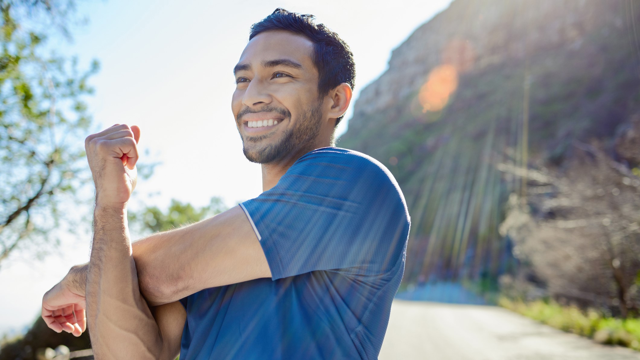 Man outside stretching arm