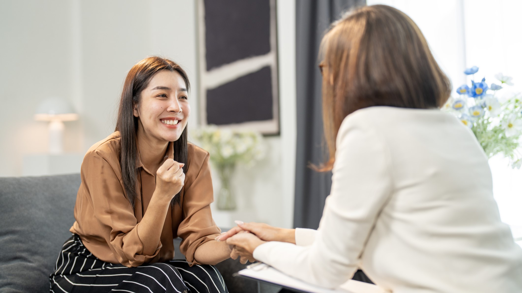 Woman speaking with a therapist holding her hand