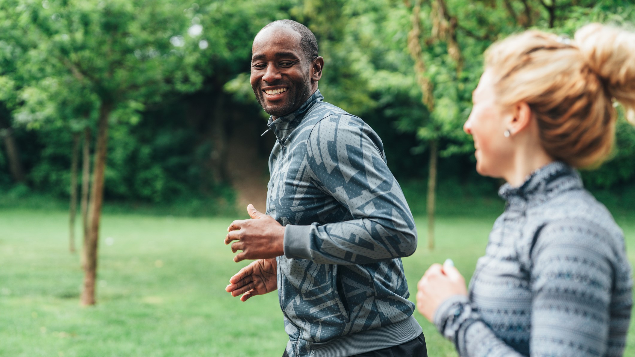 Man and woman jogging outside near trees