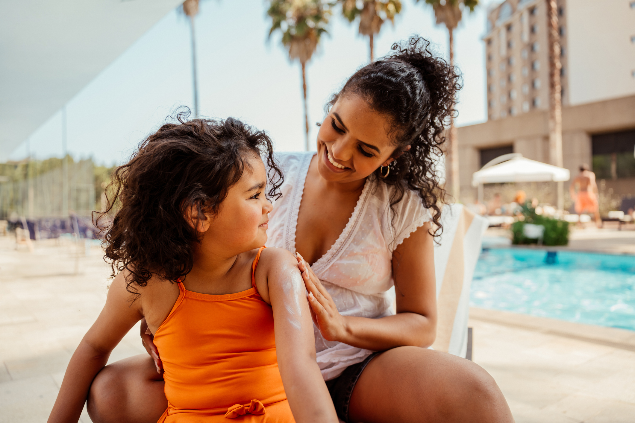 Mother putting sunscreen on her daughter before going into the pool Mother putting sunscreen on her daughter before going into the pool